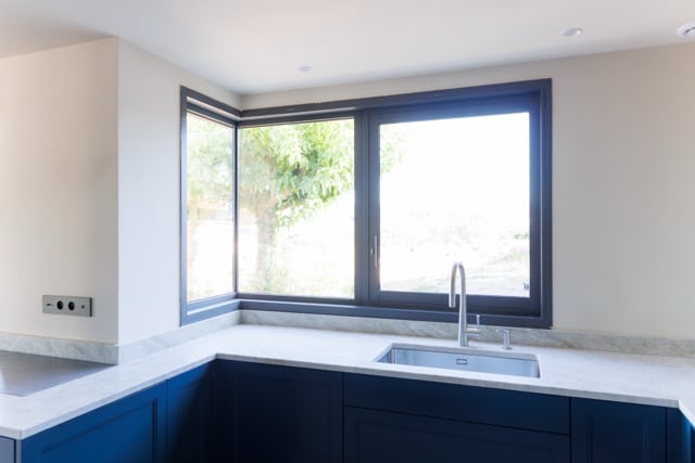 Évier sous fenêtre d’angle, robinetterie inox, coupes propres des plans minéraux, réservations invisibles — préparation cuisine DOMTY Construction à Saint-Cyr-sur-Mer.