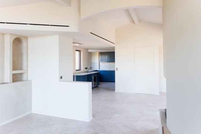 Vue d’ensemble cuisine haut de gamme : linéaires bleus, péninsule, sols pierre, alignements parfaits — préparation réseaux et supports DOMTY Construction à Bandol.